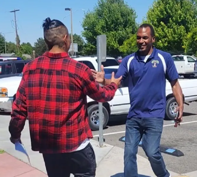 Founder Tobaski Snipes greeting a young man in a parking lot