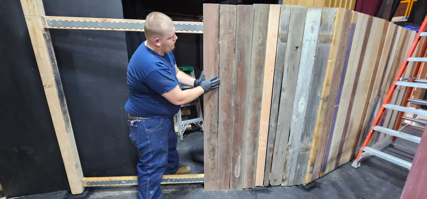 A volunteer building a wooden fence panel