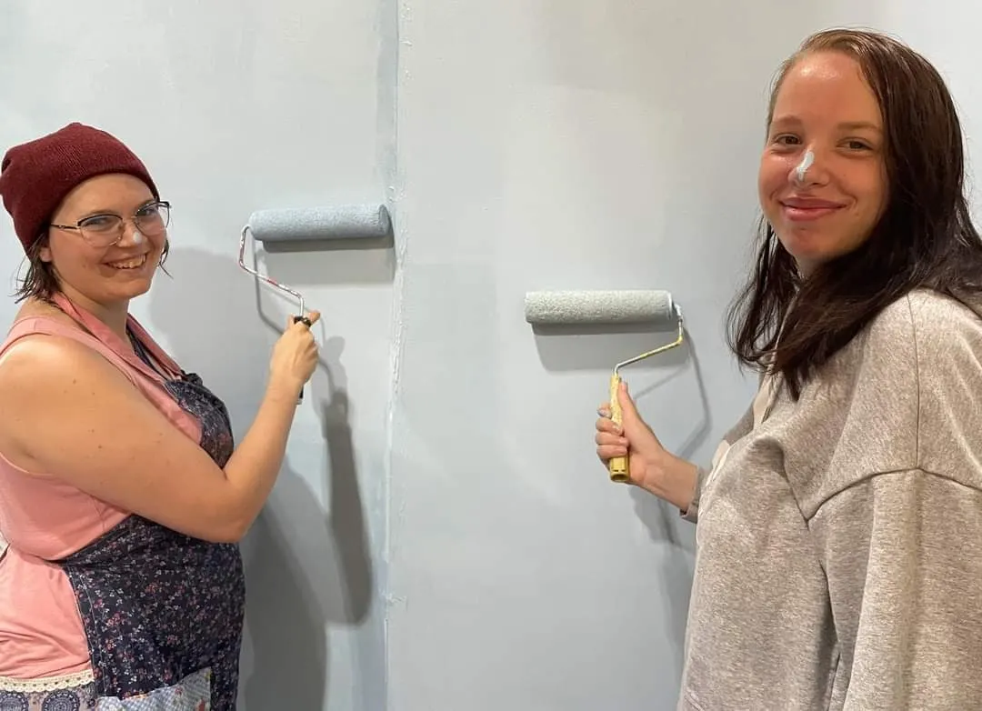 Two residents painting a wall together